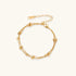 Three-strand gold-plated bracelet with clustered ball beads and adjustable clasp on cream background