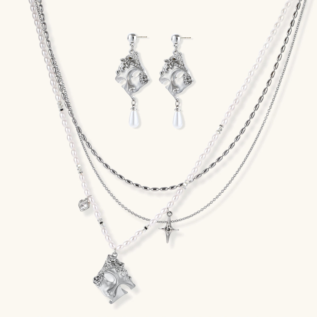 Ornate silver-toned masquerade mask jewelry set featuring rhinestone details and pearl drop earrings on white background.