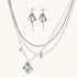 Ornate silver-toned masquerade mask jewelry set featuring rhinestone details and pearl drop earrings on white background.