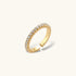 Close-up of adjustable gold-plated ring with continuous row of round zirconia stones on neutral background.